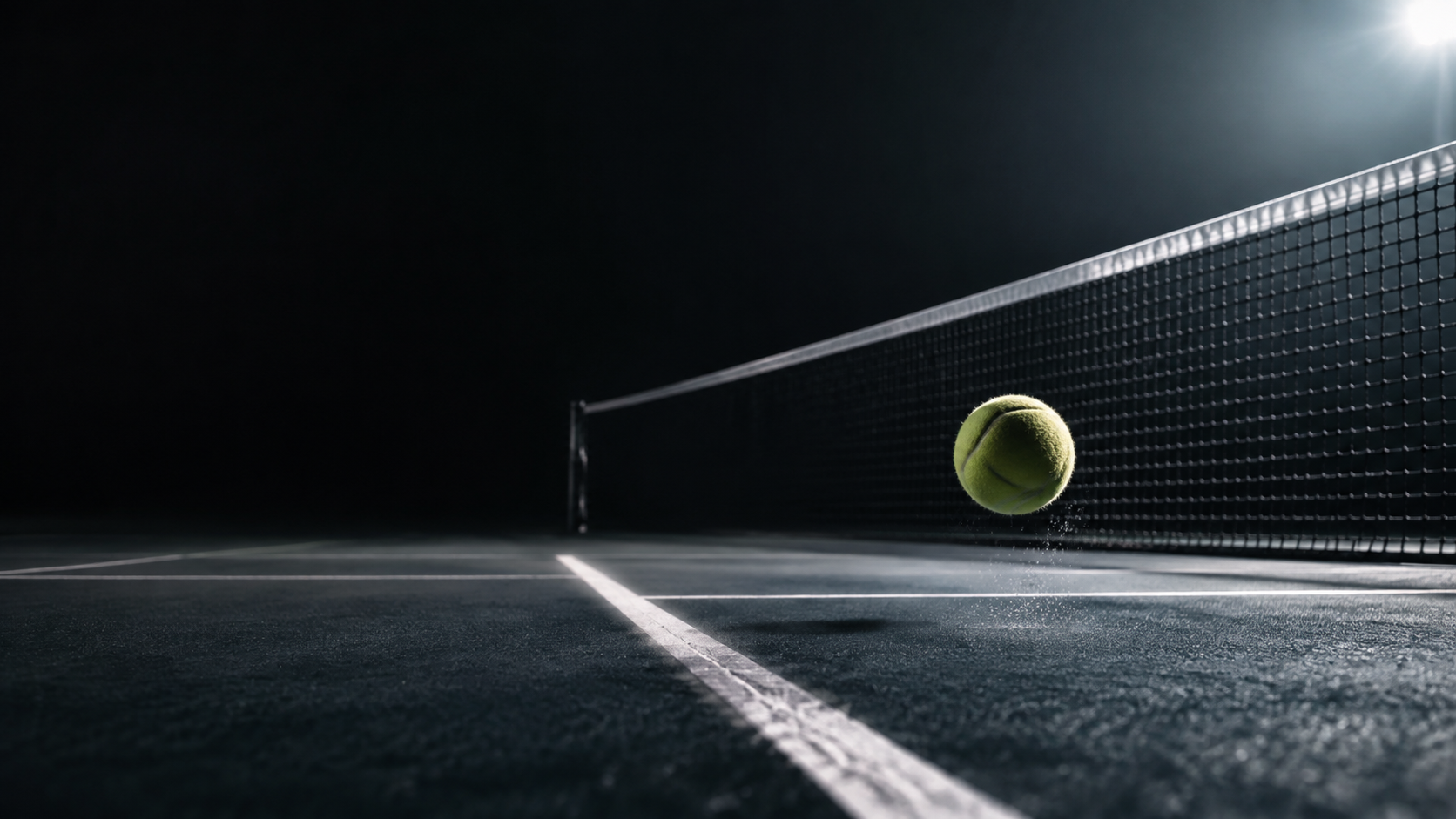A tennis ball in motion above a dark hard court